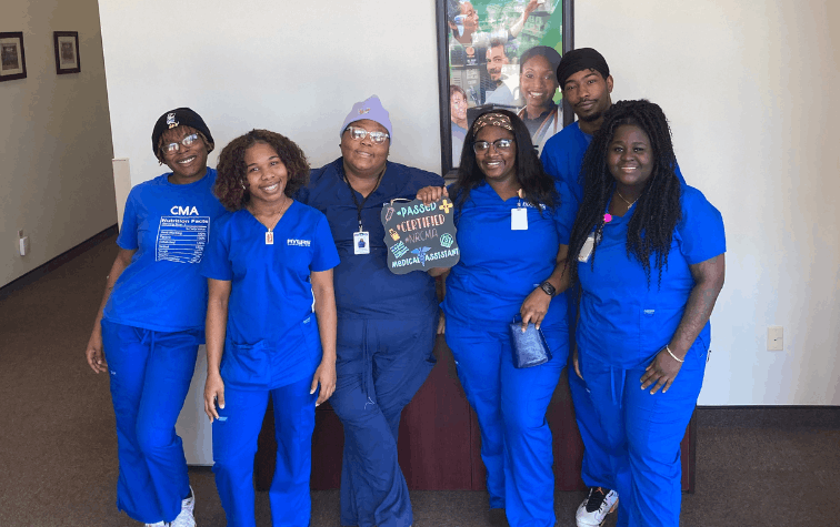 Medical Assistant students smiling, holding sign describing passing the certification test