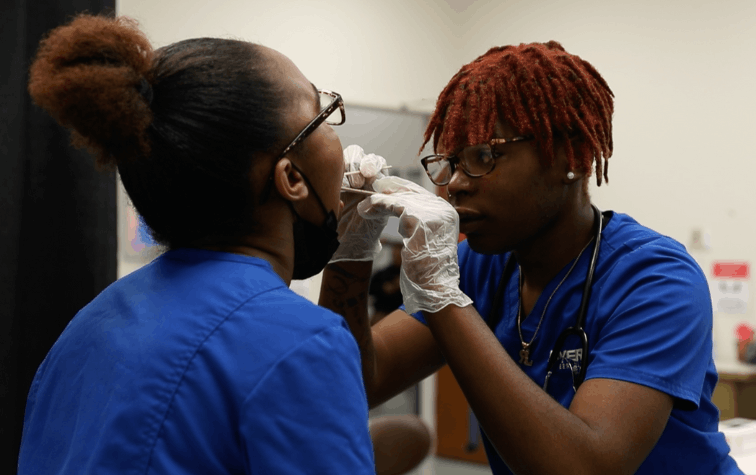 Medical assistant student examining the mouth of another student